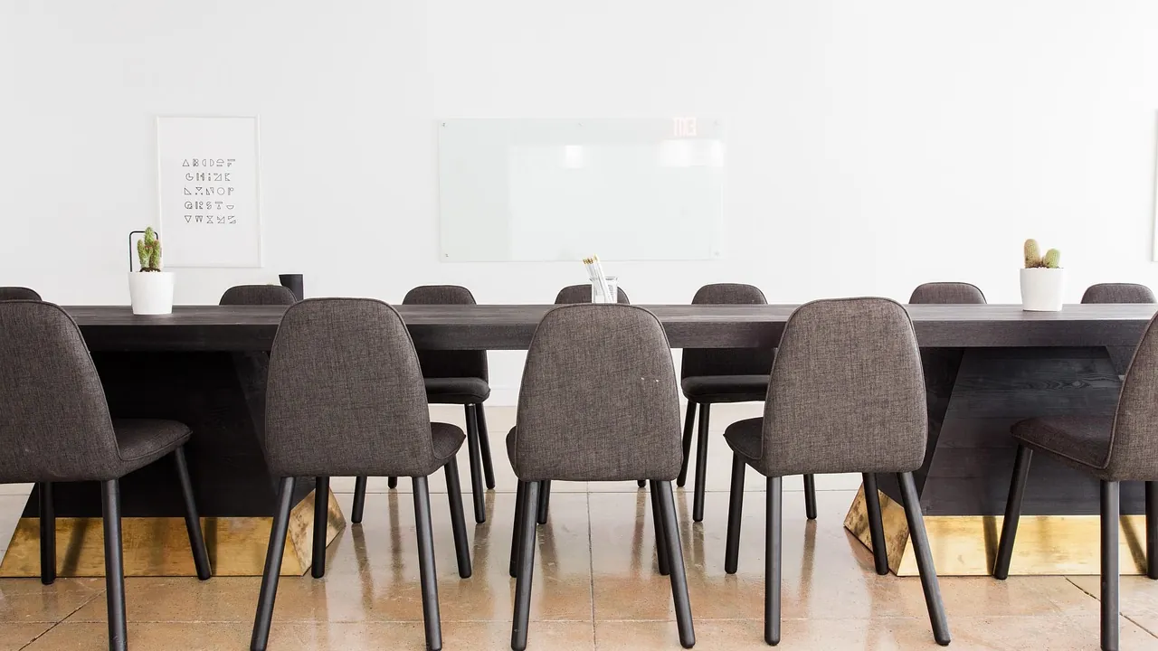 Une longue table de réunion bordée de chaises vides